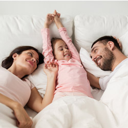 Happy rested couple with their daughter in bed